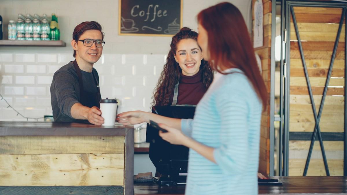 A barista handing a customer their coffee